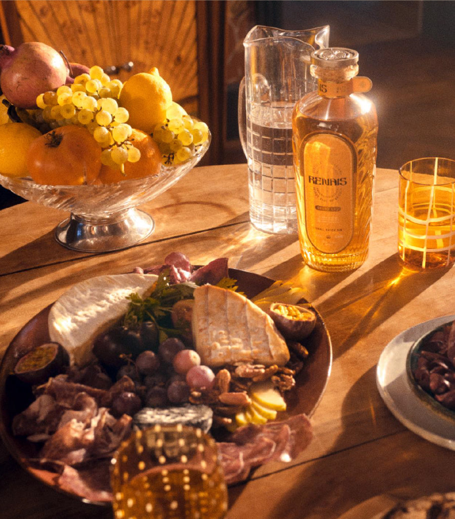 A bottle of Renais on a table with a plate of food